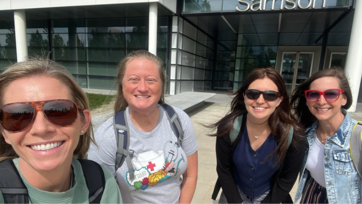 Four women smile at the camera in front of Samson Pavilion.