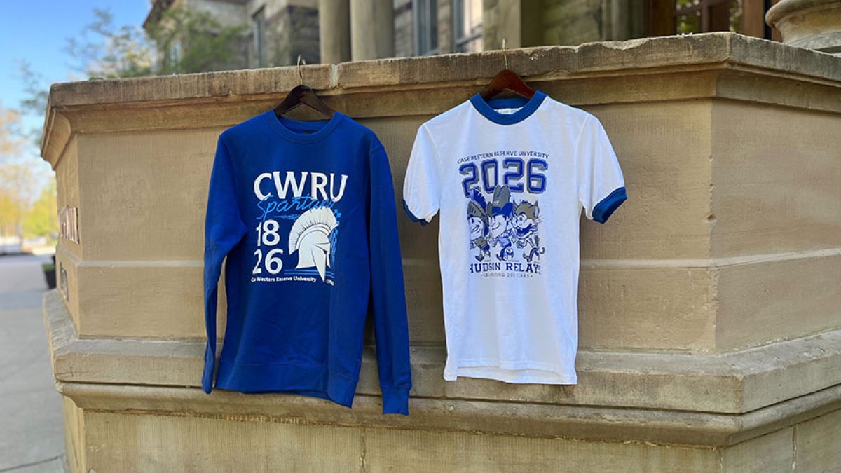 Photo showing two limited-edition Hudson Relays merch items—a t-shirt and a sweatshirt—hanging from the portico at Adelbert Hall