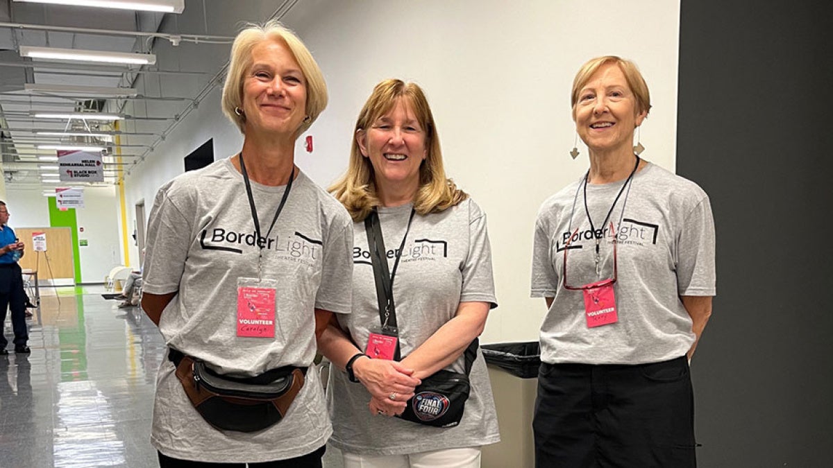 Three women wearing Borderlight Festival volunteer T-shirts pose for a photo 