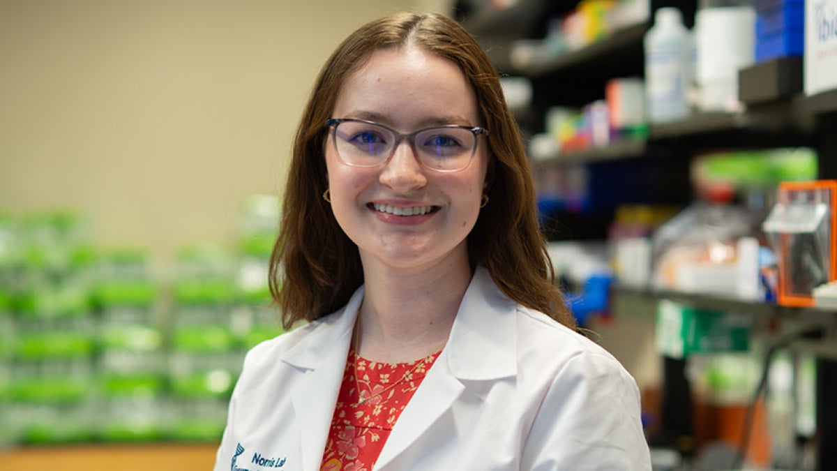 Photo of Chloe Meyer wearing a white coat in a lab setting