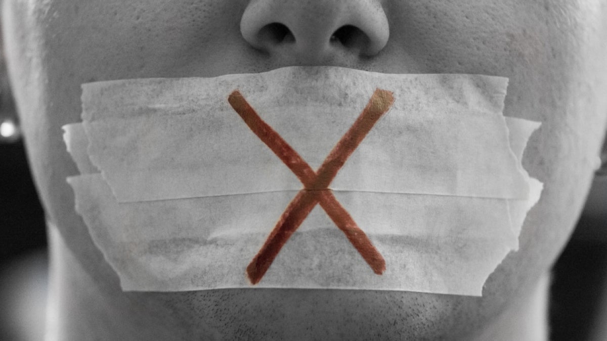 Close-up of face with tape over mouth and "X" drawn on it