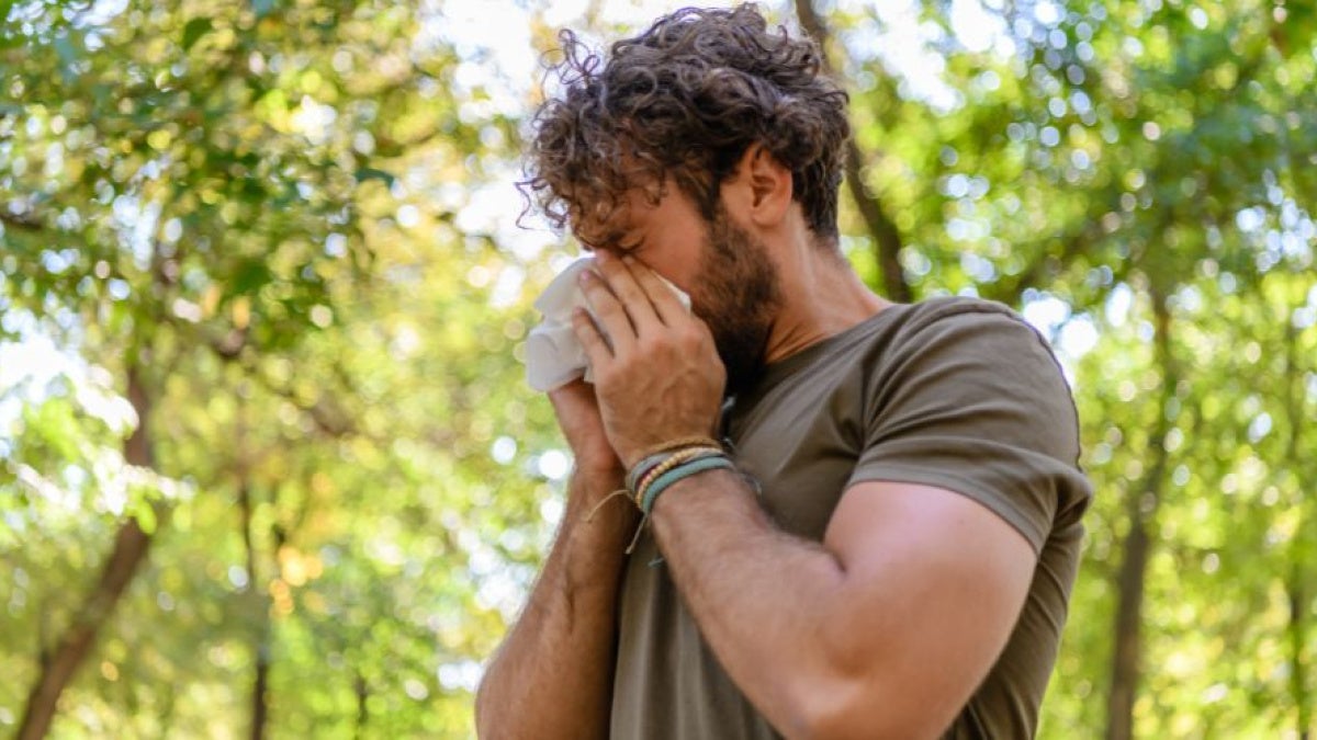 A man sneezes into a tissue