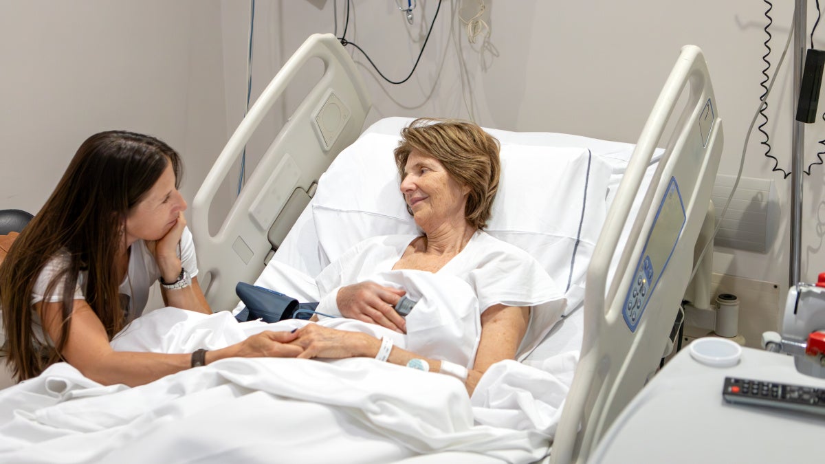 Photo of ICU patient and family member by her hospital bed.