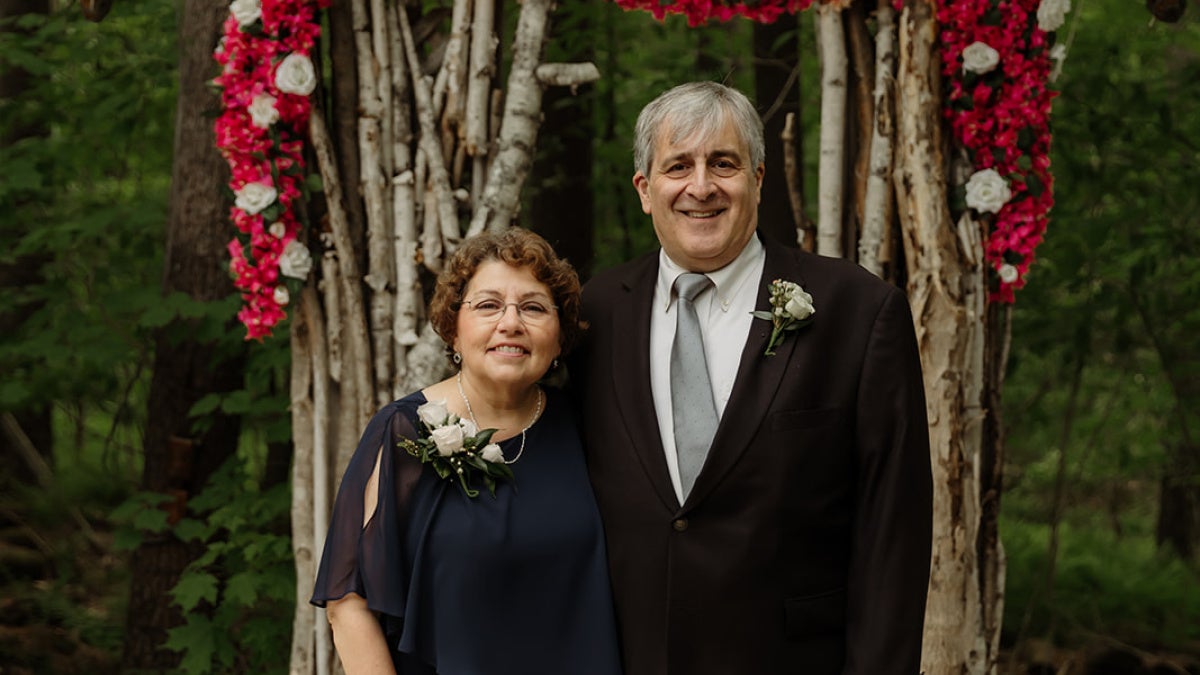 Damiano and his wife standing in front of a floral background