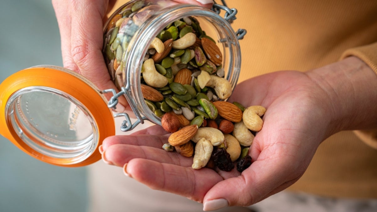 Close up of a person pouring almonds, pistachios and other nuts into their hand