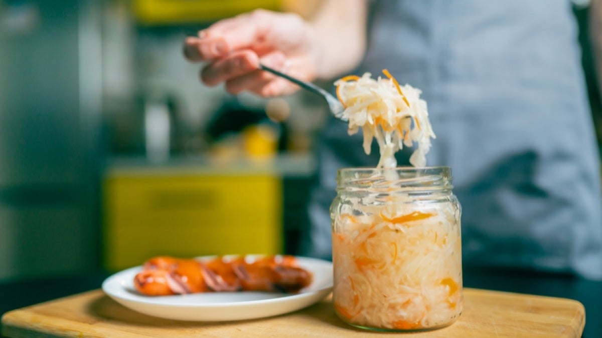 Close-up of a fork with sauerkraut and a piece of Bavarian sausage 