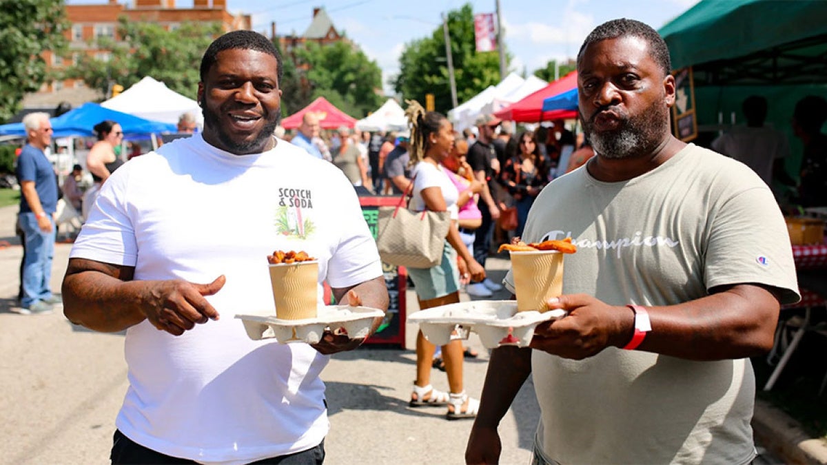 Two men pose for a photo at the Garlic Festival with a cup of food each