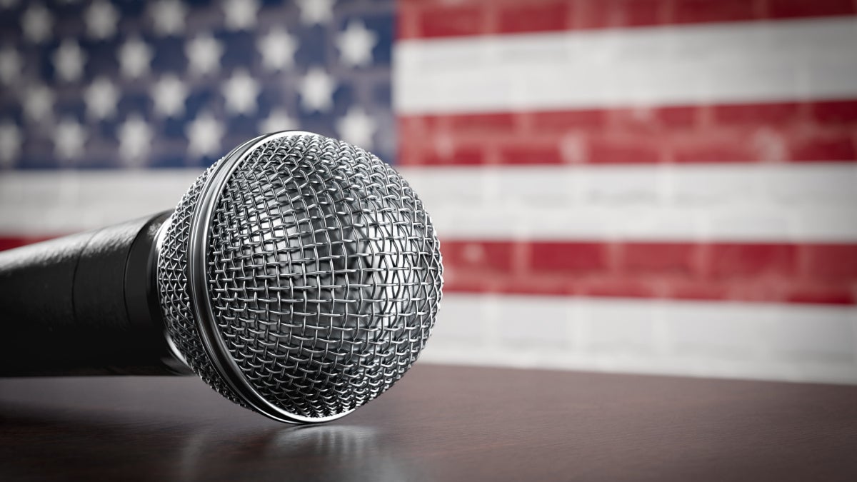 Image of a microphone with the U.S. flag in the background