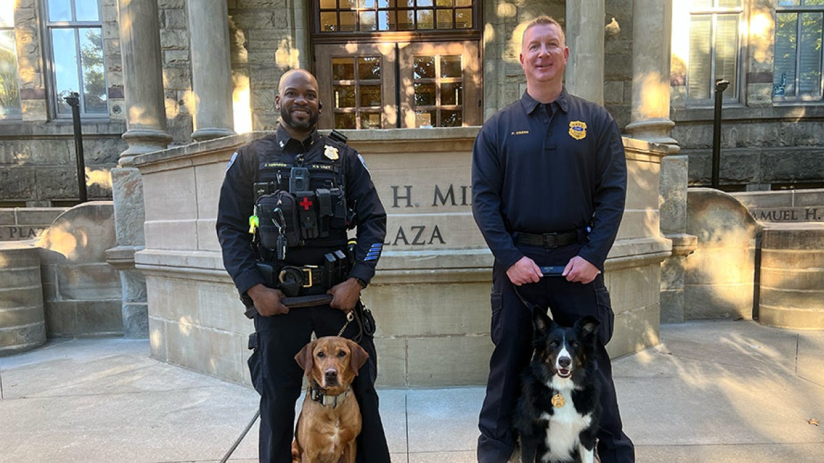 Jimiyu Edwards and Paul Owens pose for a photo with their K9s, Spartie and Maverick in front of Adelbert Hall