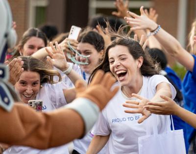 Students rush to high five and clap hands with Spartie