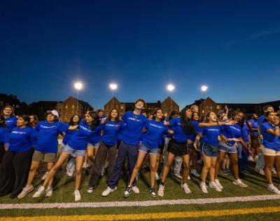 Orientation leaders link arms and belt out tunes at DiSanto Field to give new and transfer students a warm Discover Week welcome.