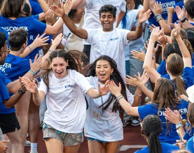 Photo of CWRU Class of 2029 students running through a tunnel of orientation leaders during Discover Week
