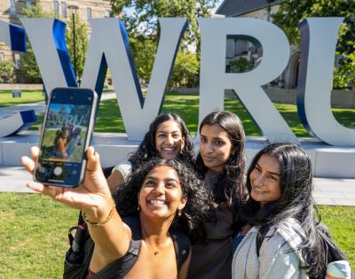 A group of students take a selfie near the big CWRU letters on the first day of classes.