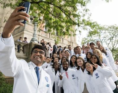 A large group of whitecoat students posing on the steps for a photo