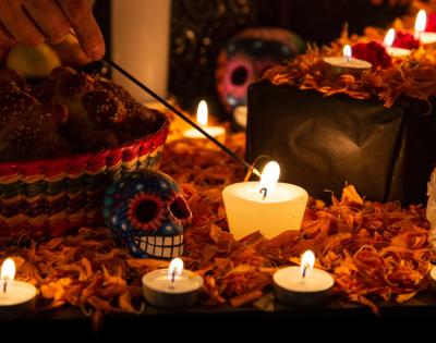 A person lights a candle sitting on an ofrenda for Dia de los Muertos (or Day of the Dead). 