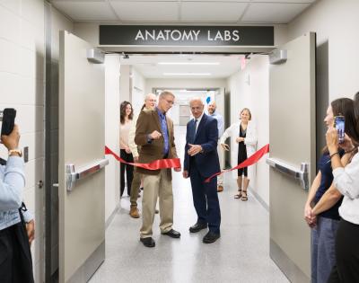 Stan Gerson and Darin Croft cutting a red ribbon at the doors of the new anatomy lab