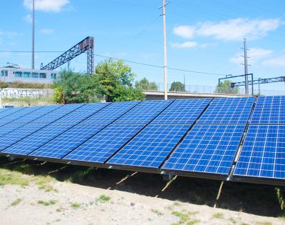 Photograph of rows of solar panels aligned in a field at a photovoltaic power plant in Cleveland.