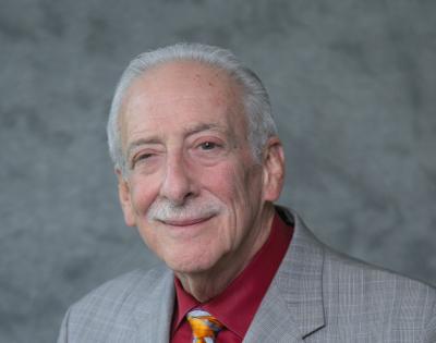 Man wearing grey jacket with a orange tie and maroon shirt