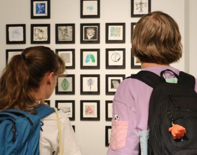 Back view of students looking at a display at Sears think[box]'s Open Print Exchange exhibit. 