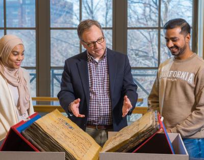 William "Bill" Claspy showcases vintage book with two members of the CWRU community. 