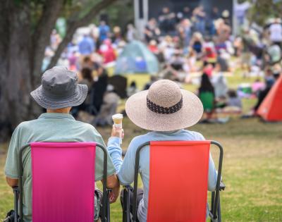 Photo of an elderly couple sitting next to one another in lawn chairs at an outdoor event