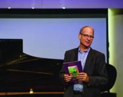 Gary Von Lehmden talking in front of a piano