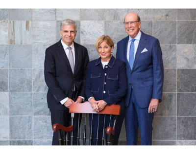 Three people standing behind a chair