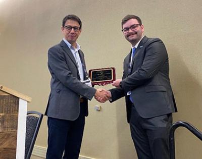 Photo of two men shaking hands as one accepts an award