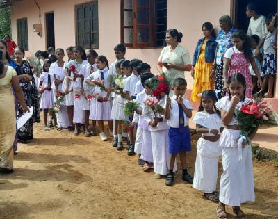 Village children of Boralanda standing in front of a building holding flowers