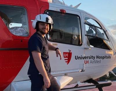 CRNA student Robert Sharkey stands in front of a medical helicopter on a rooftop.