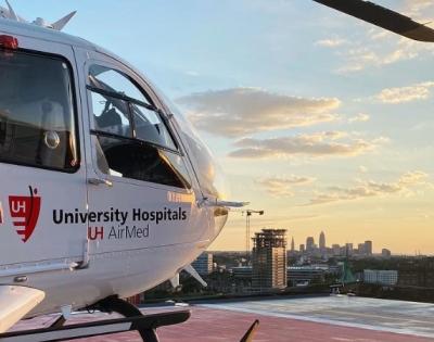 CRNA student Robert Sharkey stands in front of a medical helicopter on a rooftop.