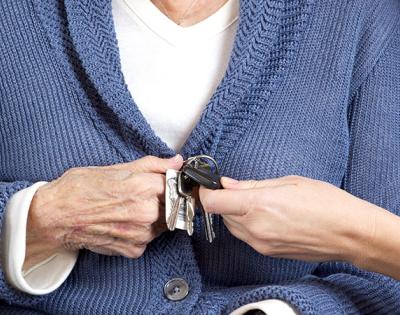 Photo of an elderly woman handing car keys to another person