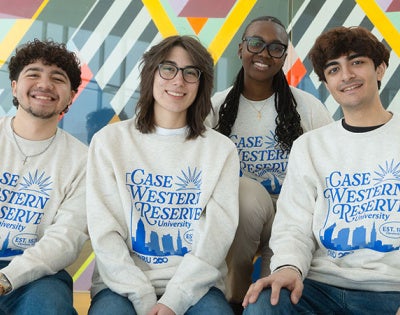 Photo of four students sitting in Tinkham Veale University Center wearing a limited-edition BlueCWRU sweatshirt