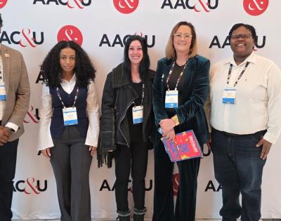Photo of five people posing for a photo at a conference