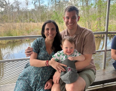 Alexander Richards riding in a boat on a bayou with his wife and child