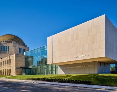 Modern performing arts center with a mix of glass and stone architecture, featuring a large domed building
