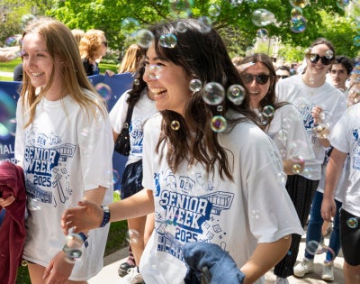 Happy Class of 2025 graduates walk through bubbles at CWRU's annual clap out celebration. 