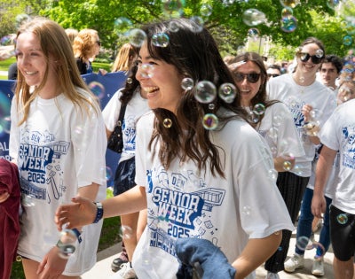 Happy Class of 2025 graduates walk through bubbles at CWRU's annual clap out celebration. 