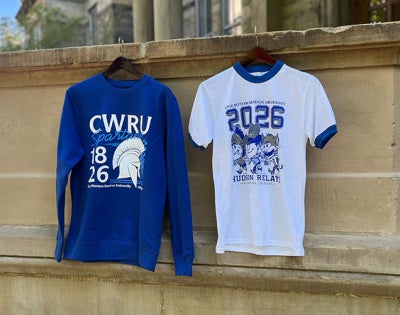 Photo showing two limited-edition Hudson Relays merch items—a t-shirt and a sweatshirt—hanging from the portico at Adelbert Hall