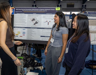 Photo of students presenting a poster at Intersections in fall 2025