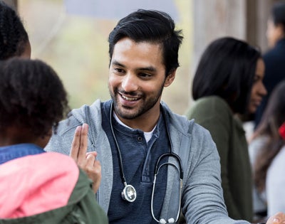 Photo of a doctor smiling while talking to a mom and her young child in a health clinic