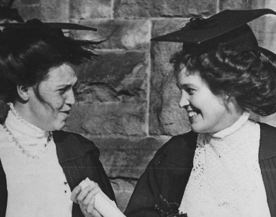A black and white photo of two women wearing academic robes