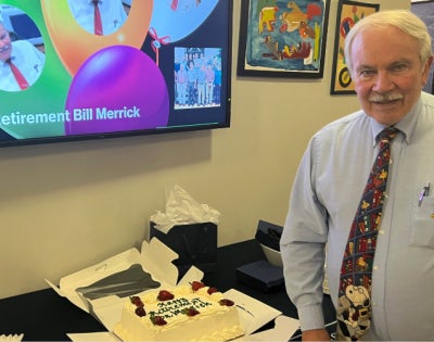 Bill Merrick posing with a cake at his retirement party