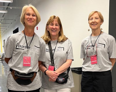 Three women wearing Borderlight Festival volunteer T-shirts pose for a photo 
