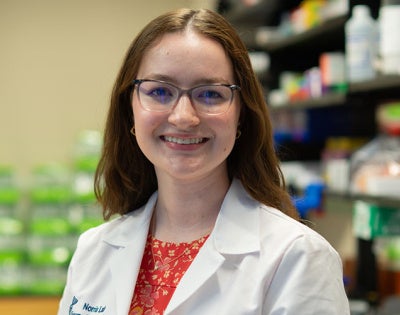 Photo of Chloe Meyer wearing a white coat in a lab setting