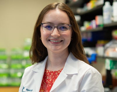 Photo of Chloe Meyer wearing a white coat in a lab setting