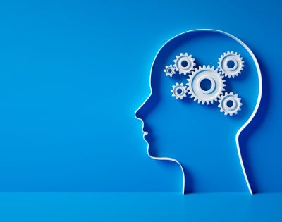 3D silhouette of a head with gear mechanics symbol against blue wall 
