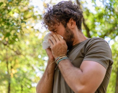 A man sneezes into a tissue