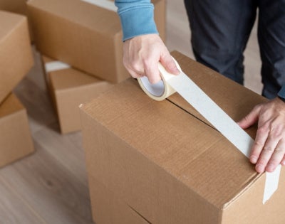 Close up of a person wrapping a moving box with masking tape. 