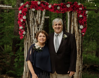 Damiano and his wife standing in front of a floral background